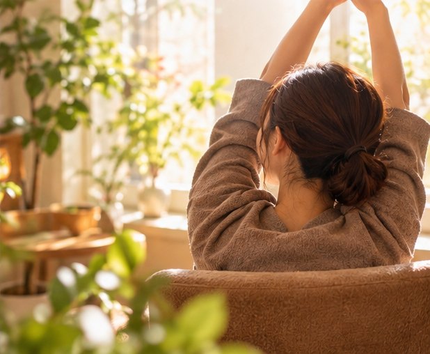 明るい朝の光の中で、気持ちよさそうに伸びをする女性の後ろ姿